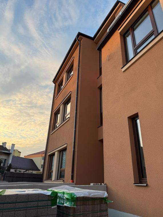 Nároží bytového domu s novou fasádou ve večerním světle