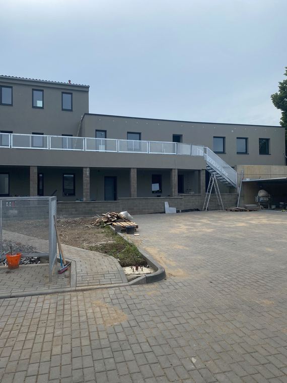 Moderní bytový komplex s dokončenou bílou fasádou a pavlačemi
